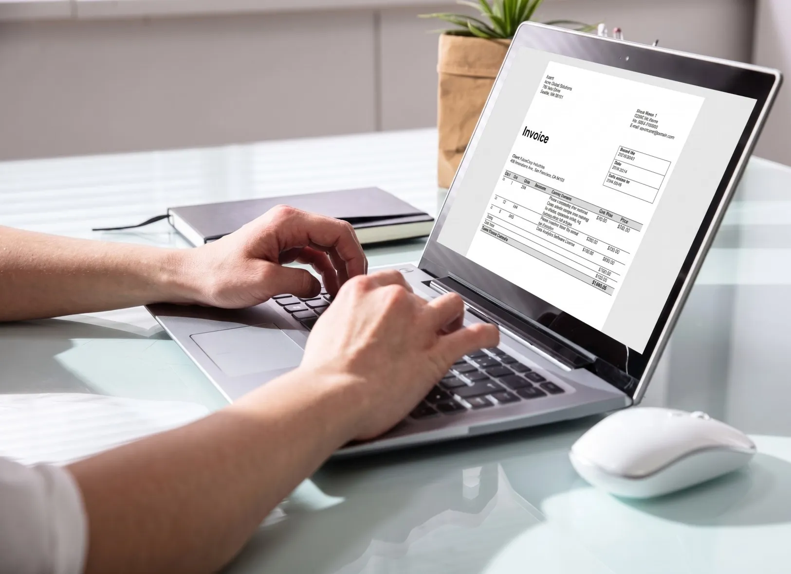Person typing on a laptop showing an invoice