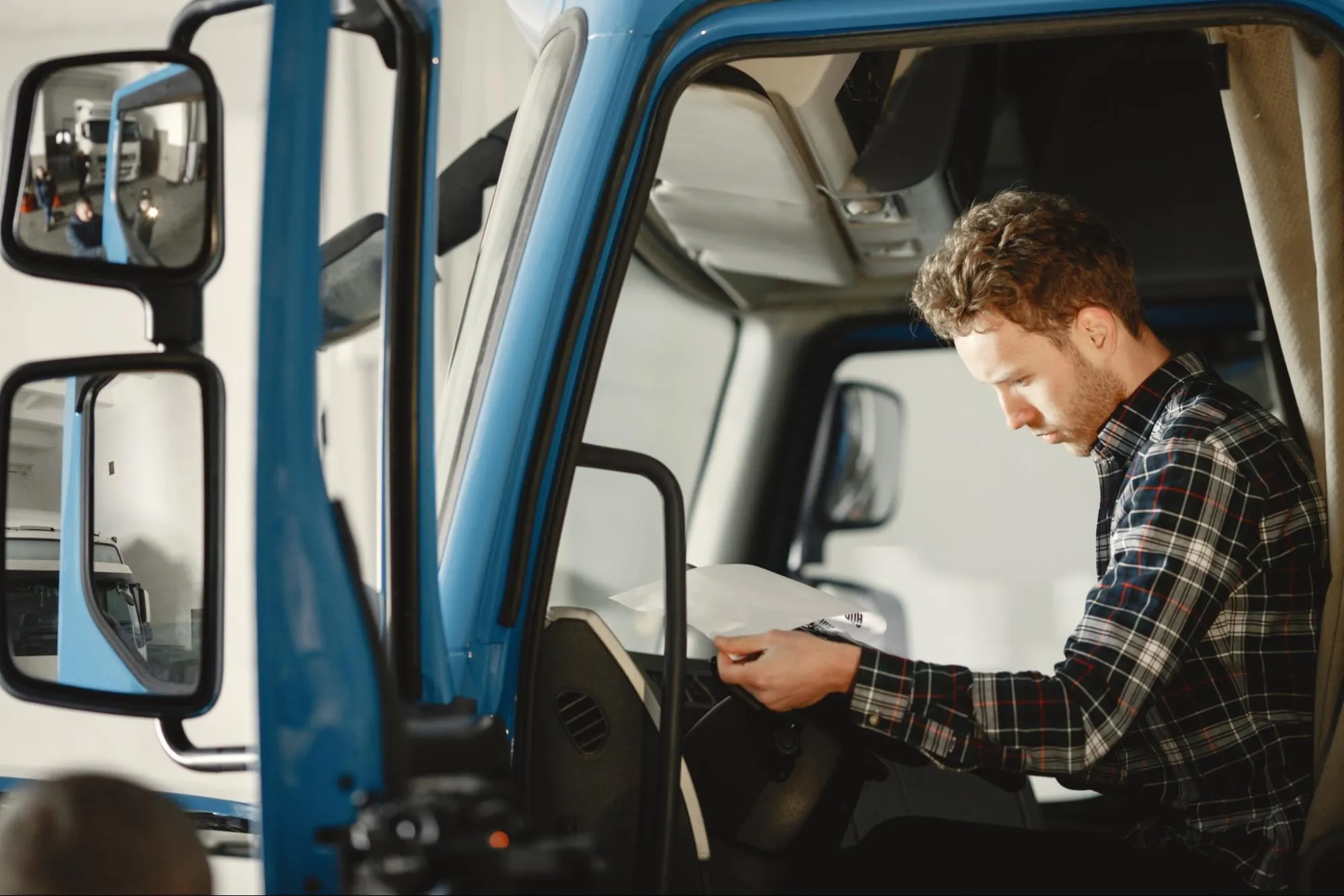 Driver sitting in a truck cab reading a paper checklist