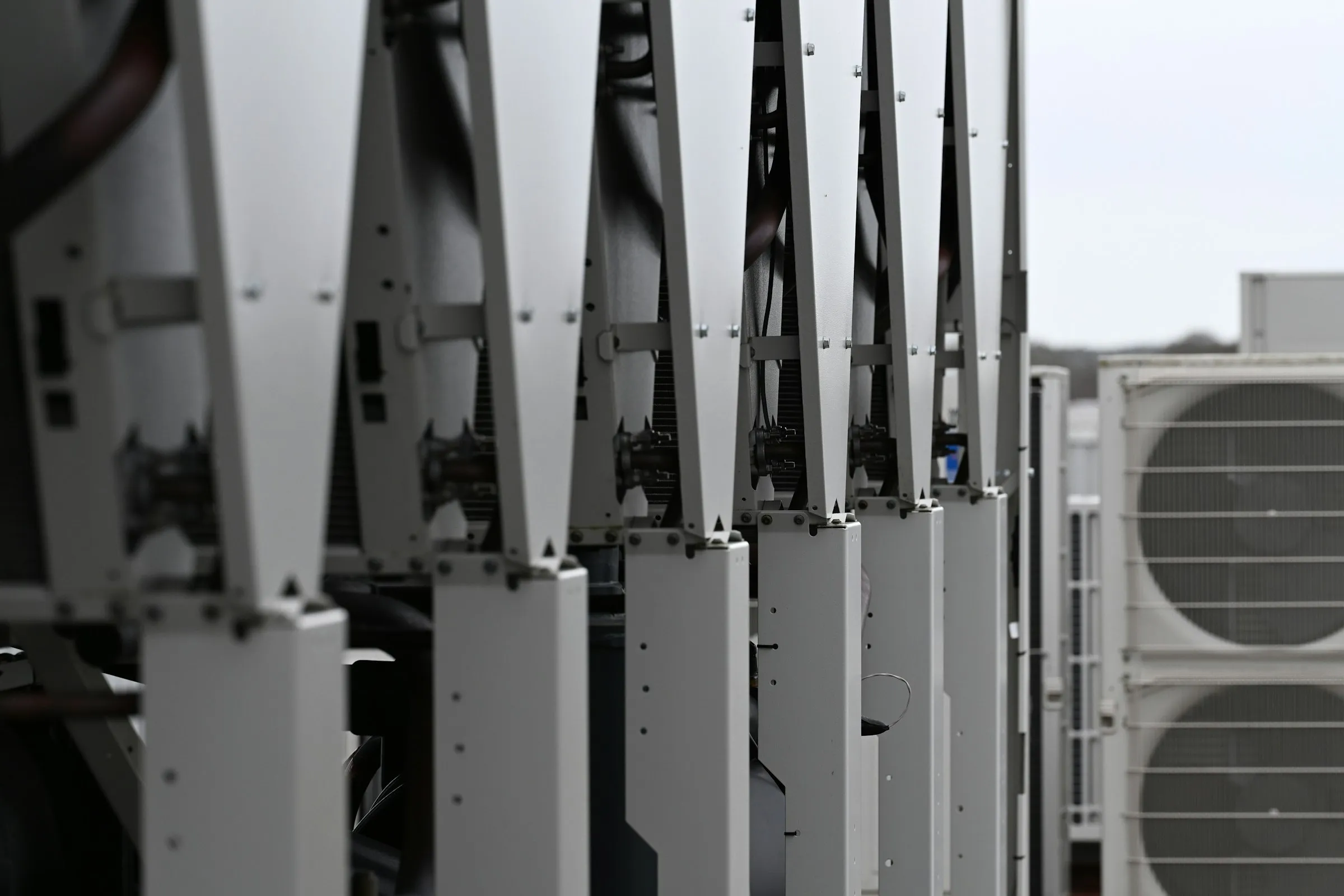 A row of rooftop chiller units with condenser fans beside them.