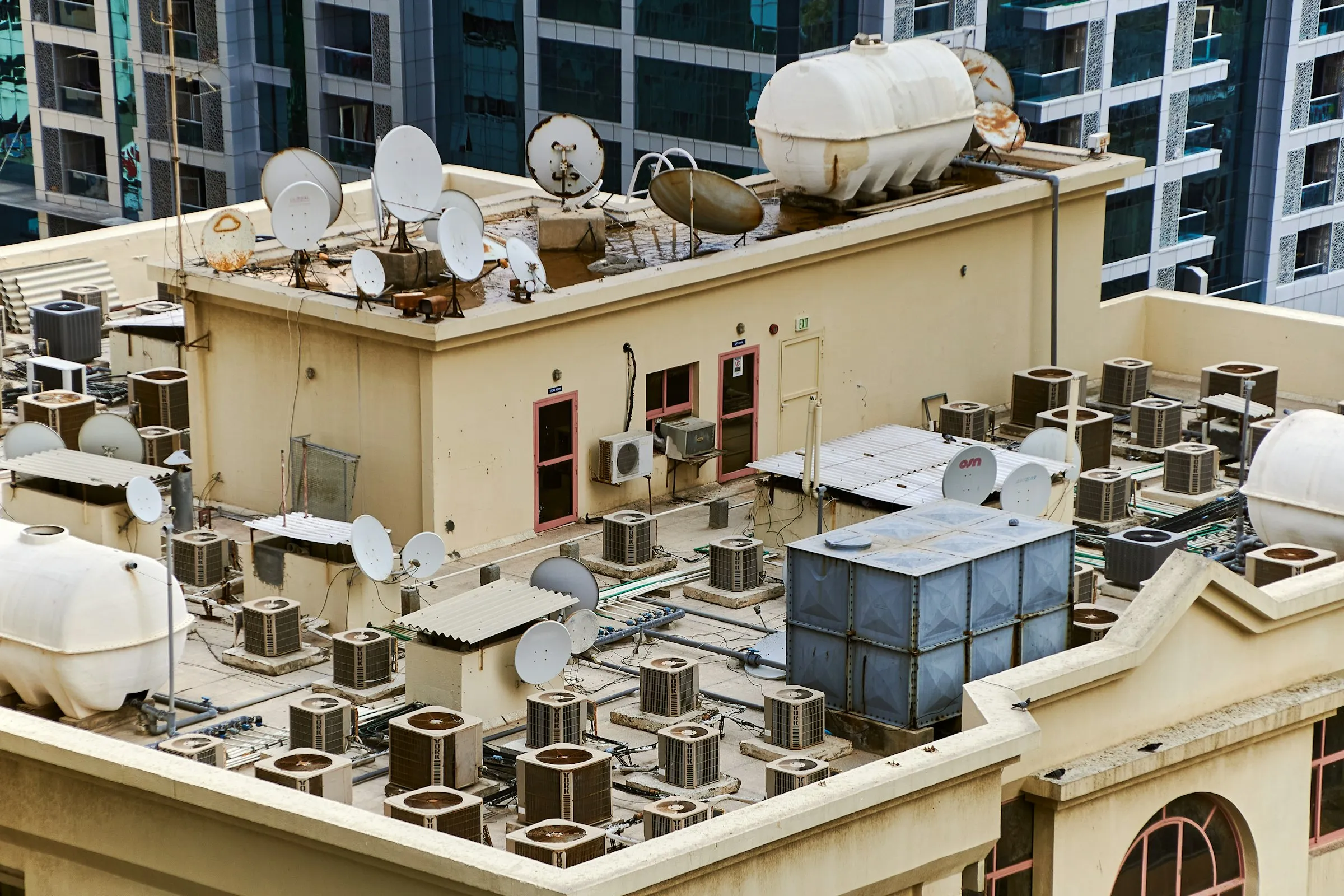 Dozens of air-conditioning condenser units, water tanks and satellite dishes cover a flat city rooftop.
