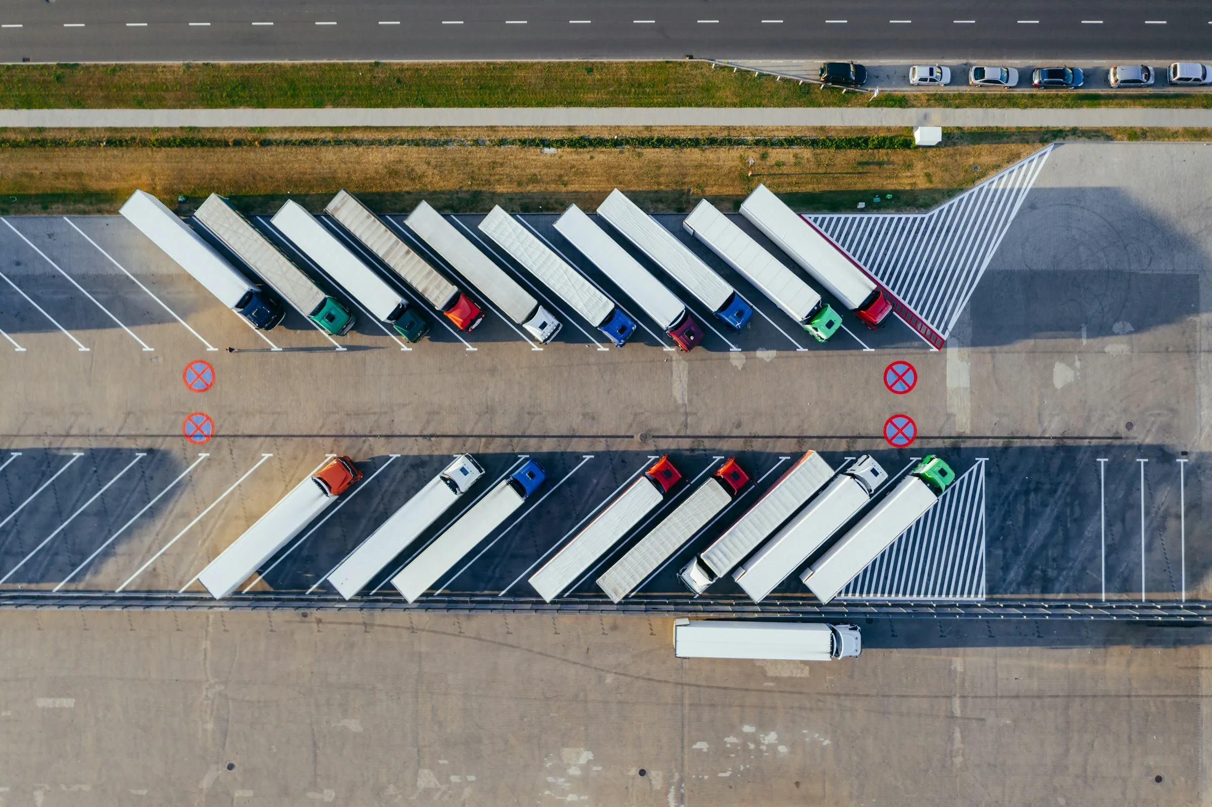 An aerial view of articulated trucks parked in angled bays at a depot yard.