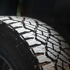 Close-up of the tread and sidewall of a large vehicle tyre mounted on a dark alloy wheel.