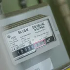 Close-up of a gas meter's label showing its serial number and a row of odometer-style digits, with the last digits highlighted in red.