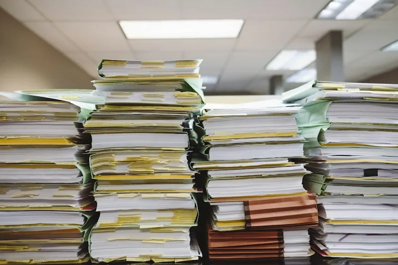 Tall stacks of paper files and folders piled up in an office